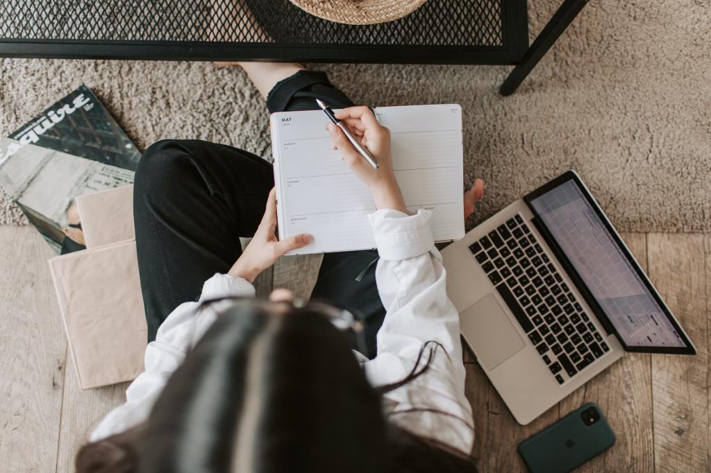 girl on the floor with her laptop and notebooks planning on her content writing
